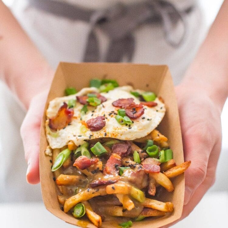 Paleo curry fries topped with an egg inside paper box.