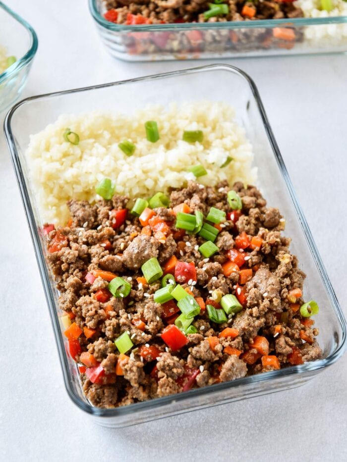 Glass meal prep container with cauliflower rice, veggies, and ginger ground beef