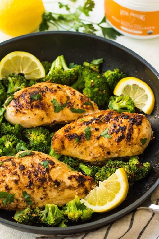 A skillet with chicken, lemon, and broccoli