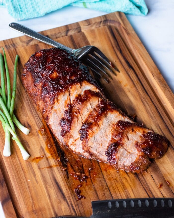 Cut Korean barbecue pork loin on a wooden cutting board with green onions