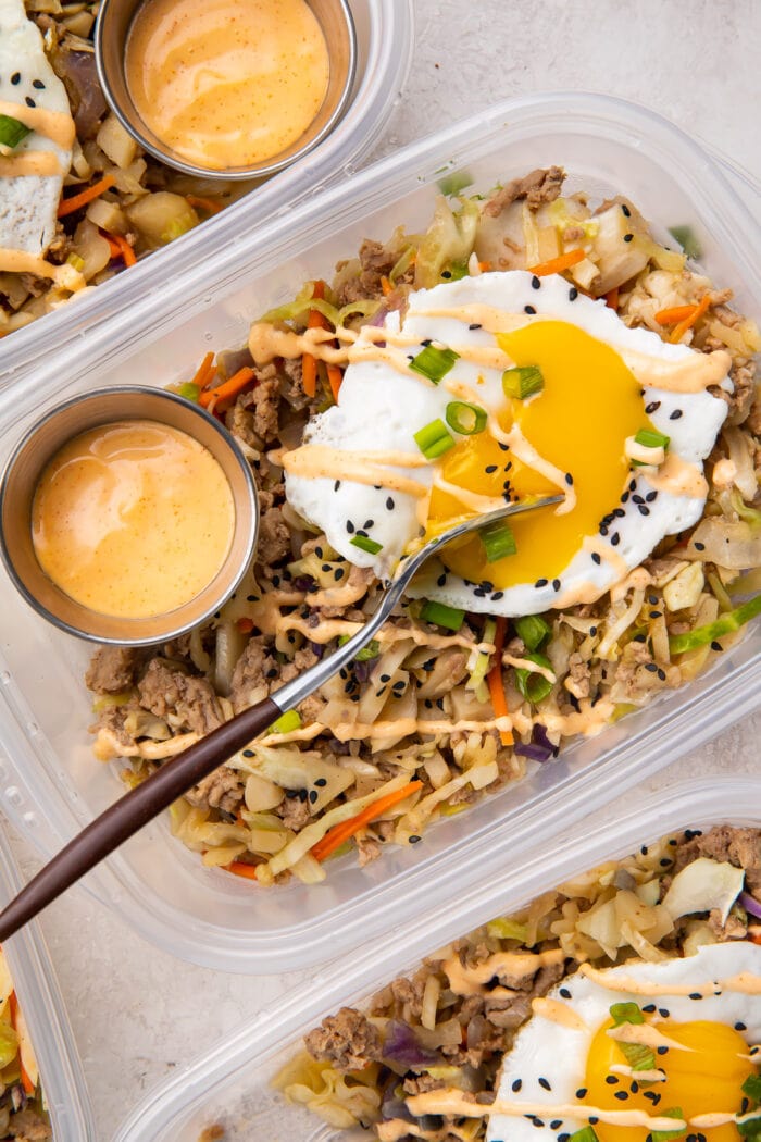 Egg roll in a bowl with a fried egg in meal prep containers