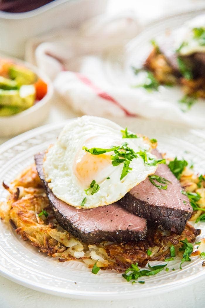 Sous vide rump roast on a white plate topped with a fried egg
