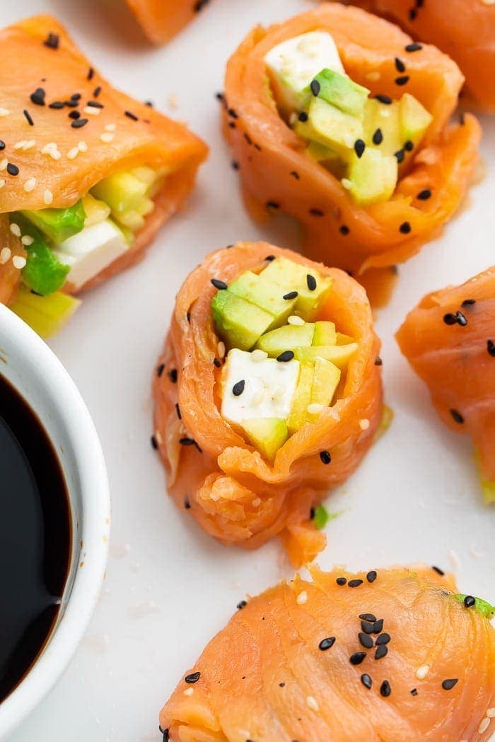 Several pieces of keto smoked salmon sushi next to a bowl of soy sauce