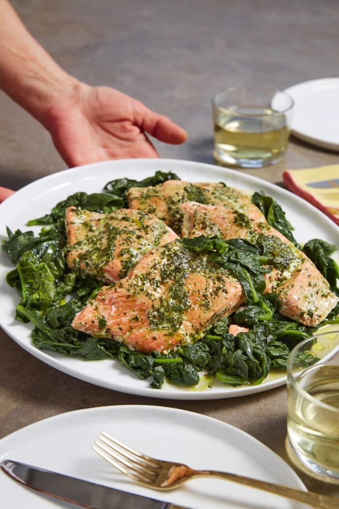 Sous vide salmon in herb butter on a plate of spinach