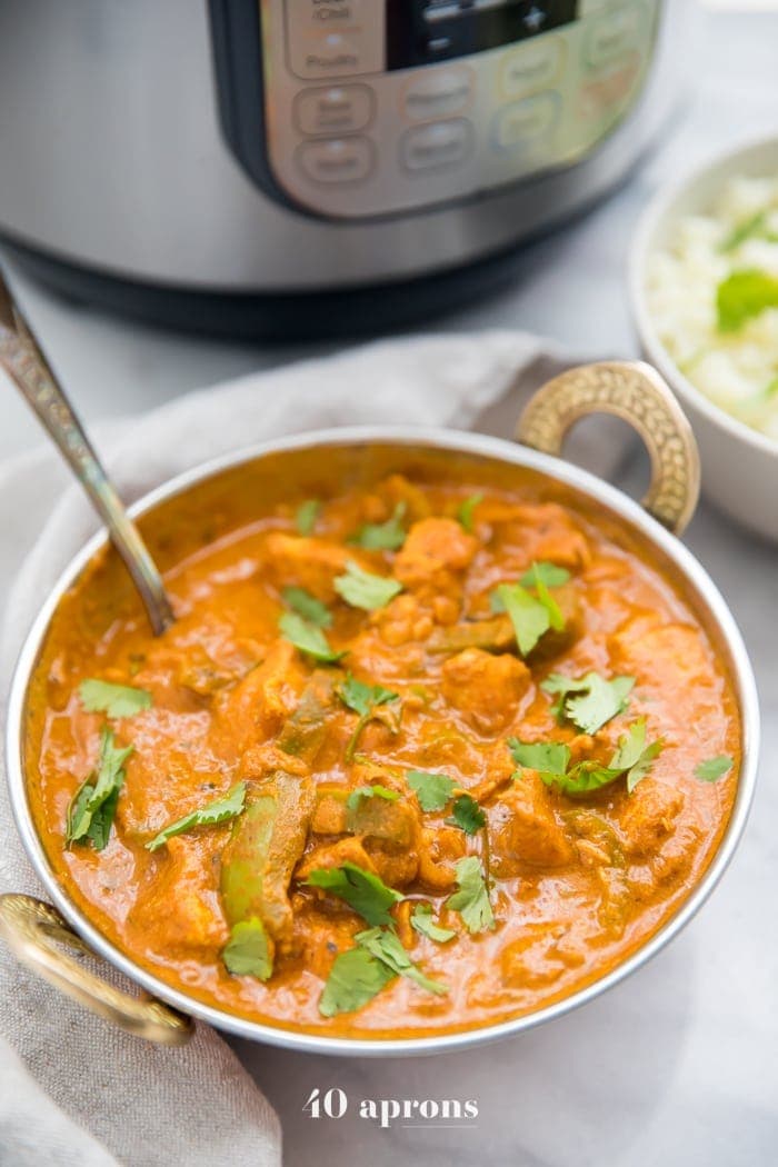 A bowl of chicken tikka masala in front of an Instant Pot
