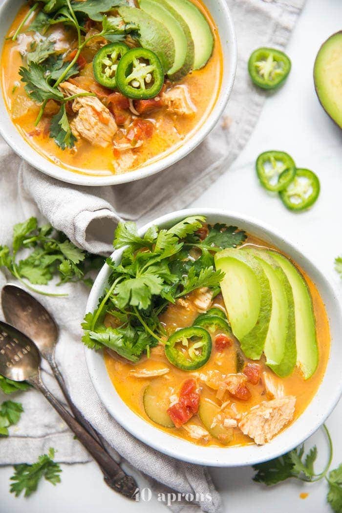 Overhead view of two bowls of low carb chicken tortilla-less soup with avocado garnish