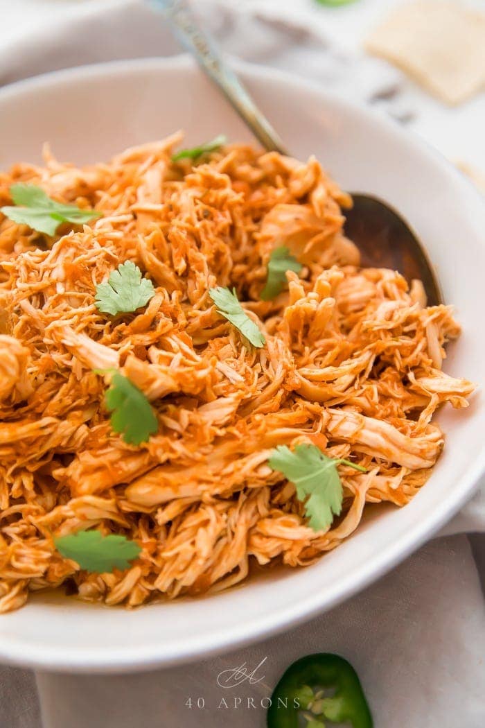 A white bowl of shredded Mexican chicken