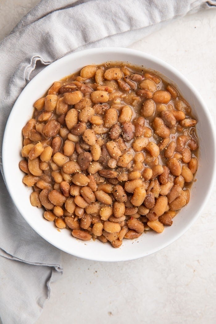 An overhead view of a white bowl holding Instant Pot cooked pinto beans