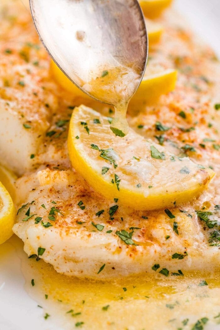 A close up of lemon garlic butter spooned over baked fish
