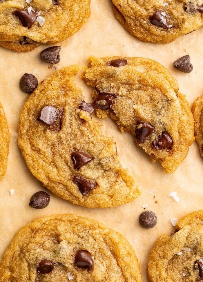 Close up of a vegan chocolate chip cookie broken in half and placed on parchment paper