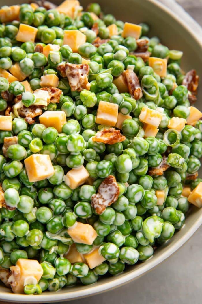Pea salad with bacon, cheddar, and green onions in a large bowl