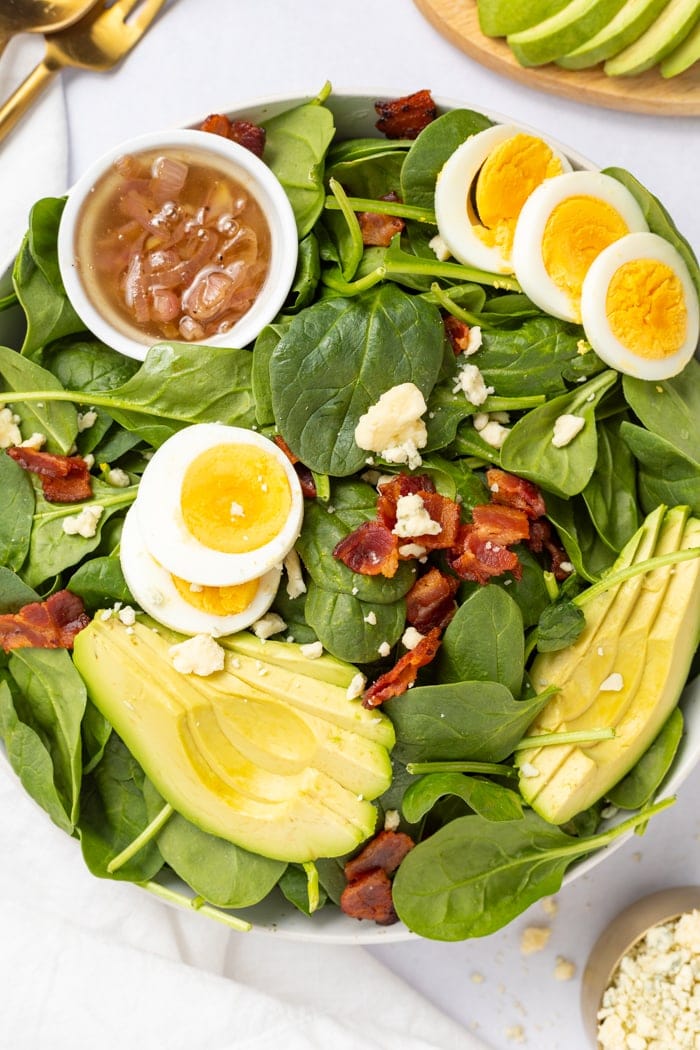 Spinach Salad overhead shot with a hot bacon dressing on the side.