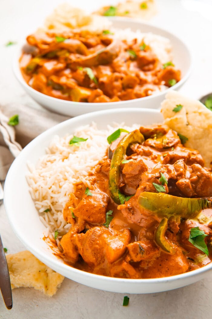 Angled photo of Instant Pot chicken tikka masala in a bowl with basmati rice and naan