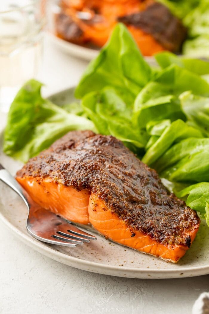 Air fryer salmon on a plate next to a small green salad