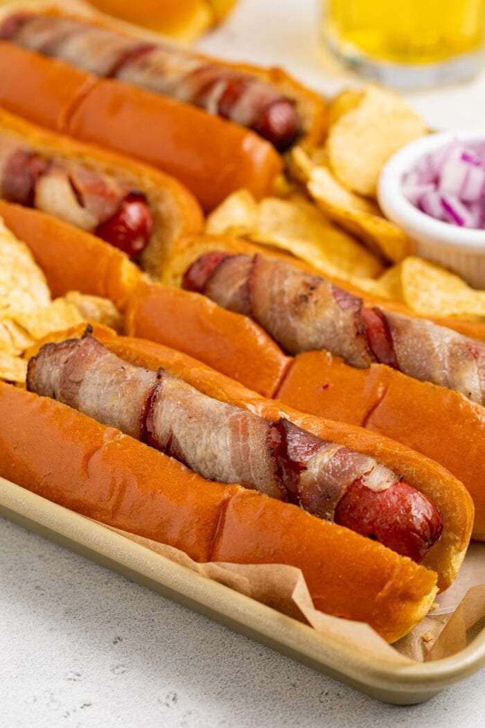 close up image of bacon wrapped hot dogs on a tray