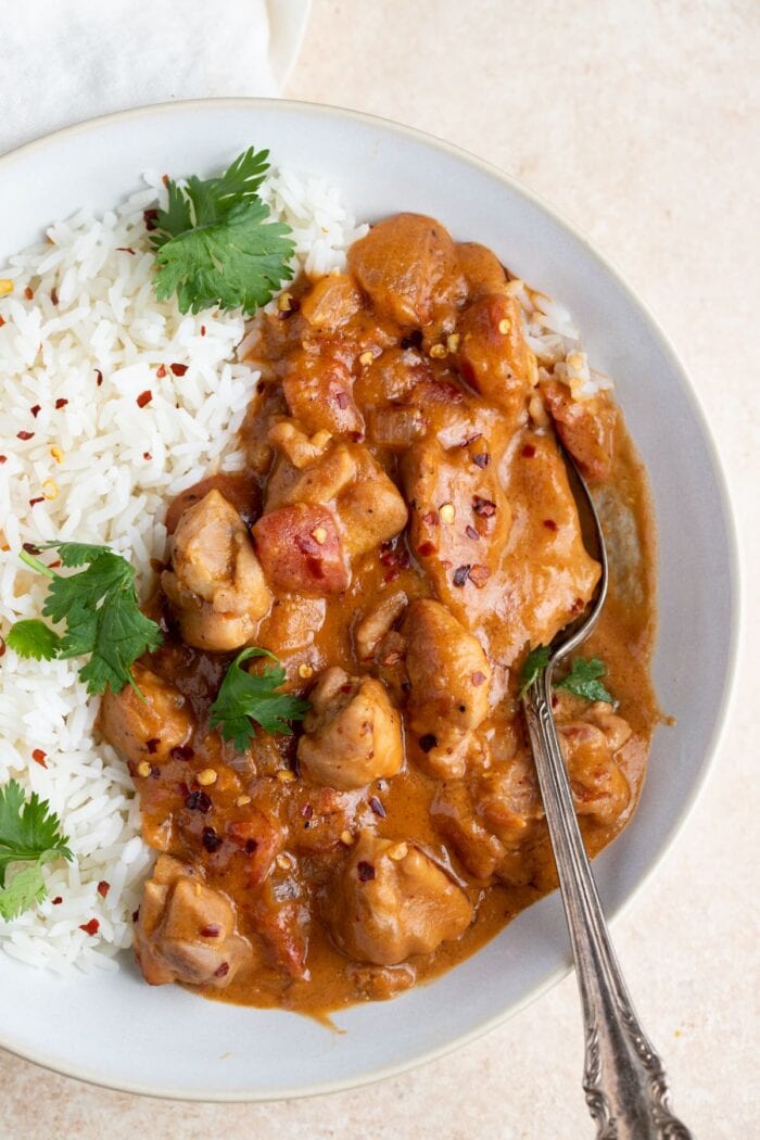 Overhead angle of peanut butter chicken and rice in a white bowl with a spoon