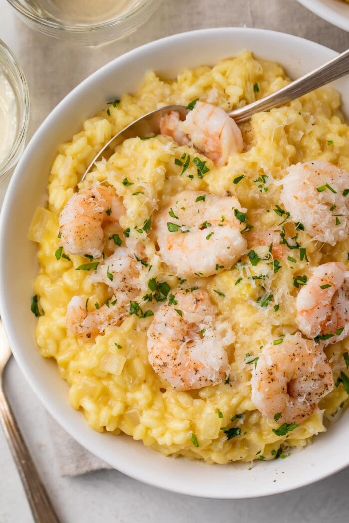 Shrimp risotto in a large white bowl with a fork