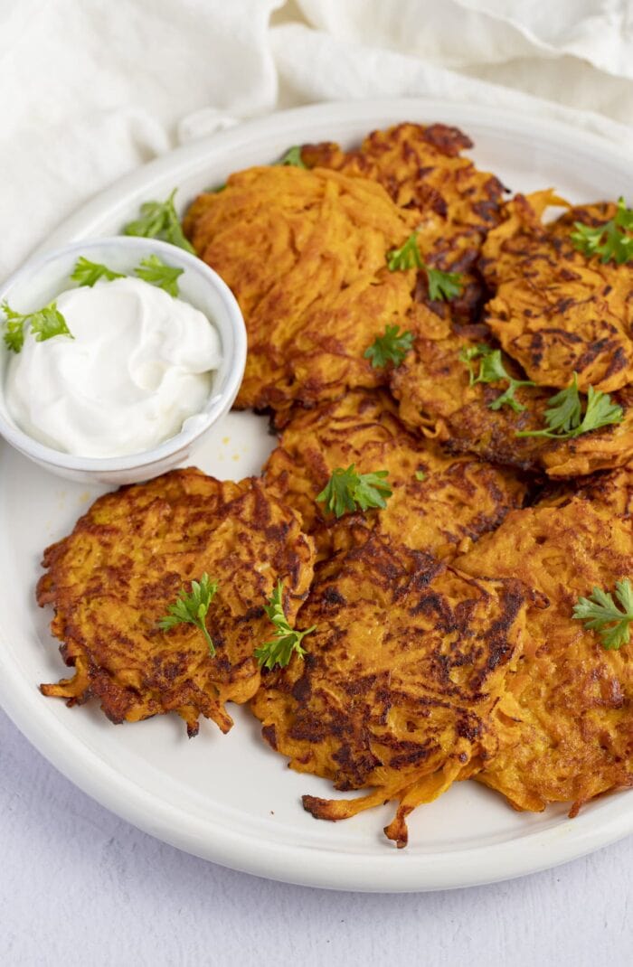 Sweet potato hash browns on a white plate next to sour cream