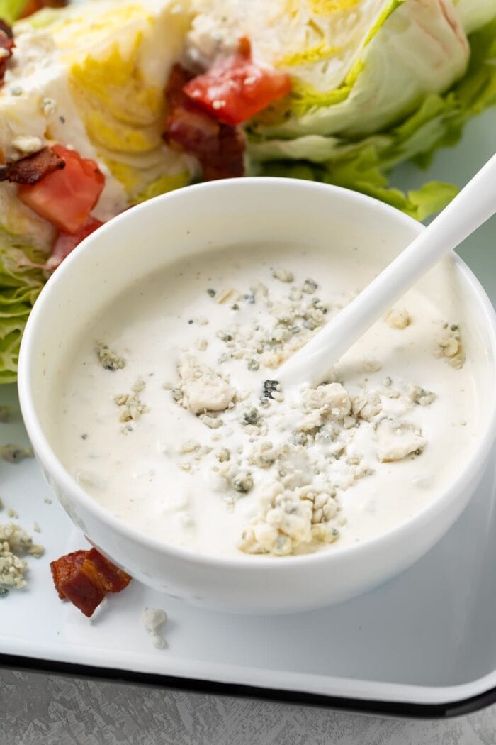 Blue cheese dressing in a small bowl next to salad