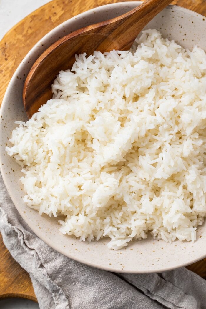 Overhead photo of Instant Pot jasmine rice in a bowl on a wooden tray with a cloth napkin