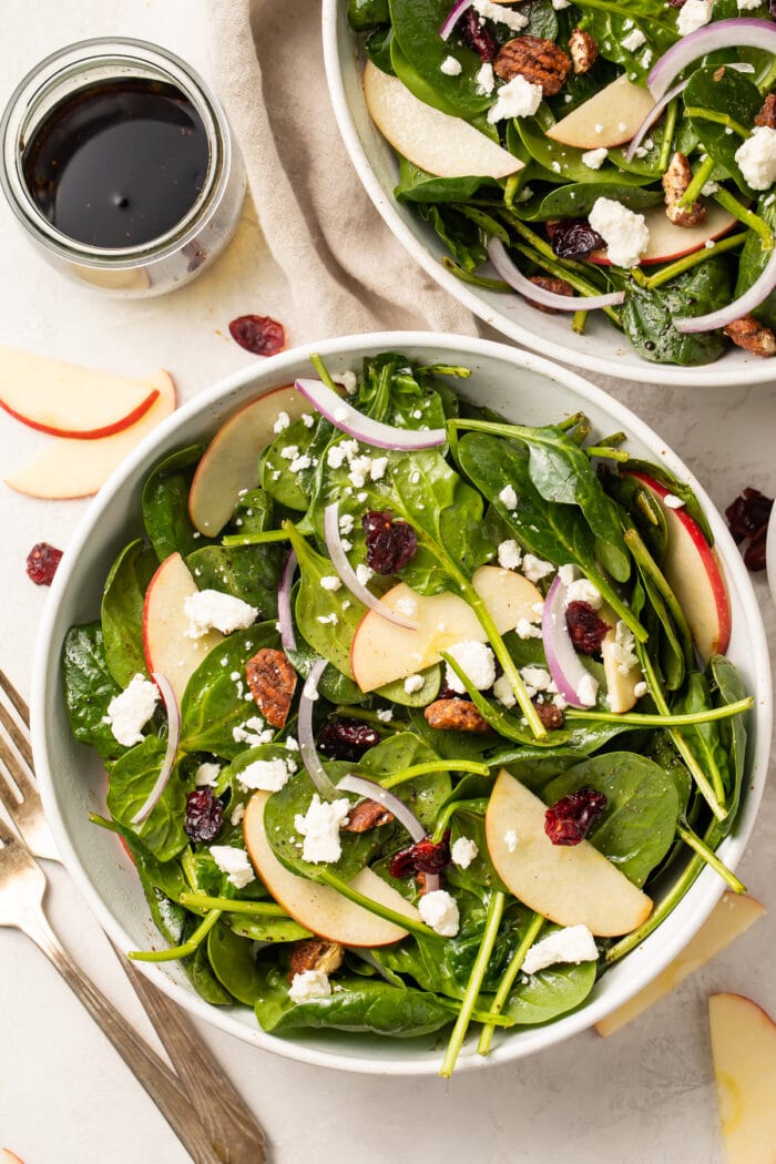 Zoomed out overhead photo of spinach salad in bowls