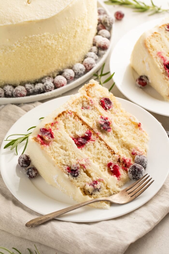 A slice of cranberry white chocolate cake on a white plate with a fork