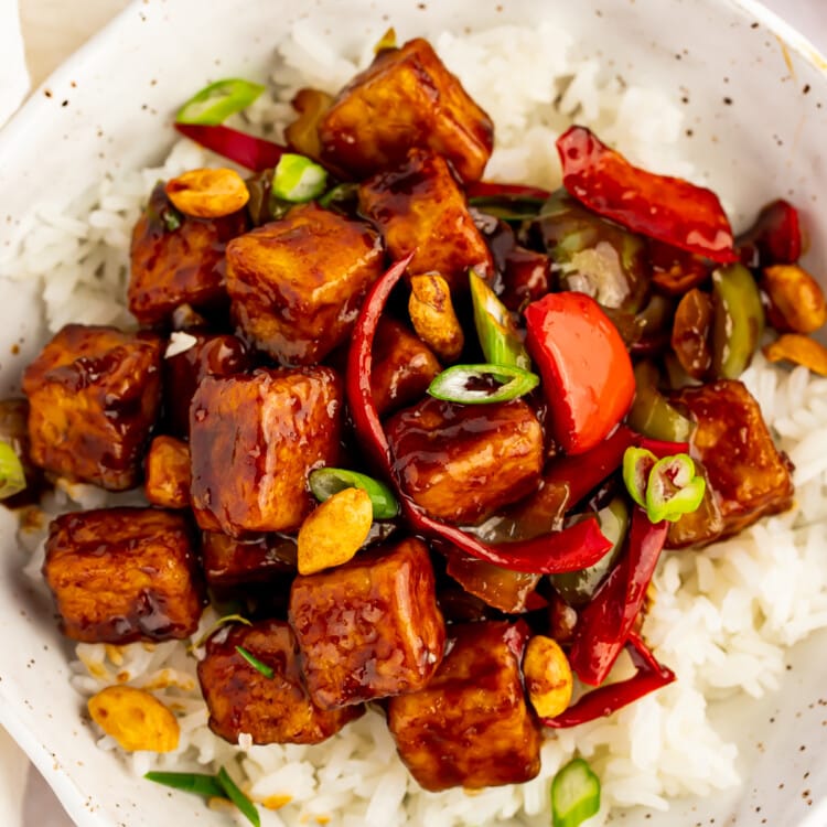 Overhead view of kung pao tofu with stir-fried veggies and white rice in a white bowl.