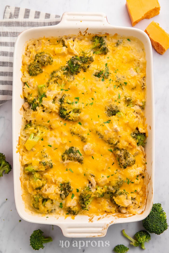 Overhead view of a white rectangular casserole dish full of cheesy chicken, broccoli, and rice.