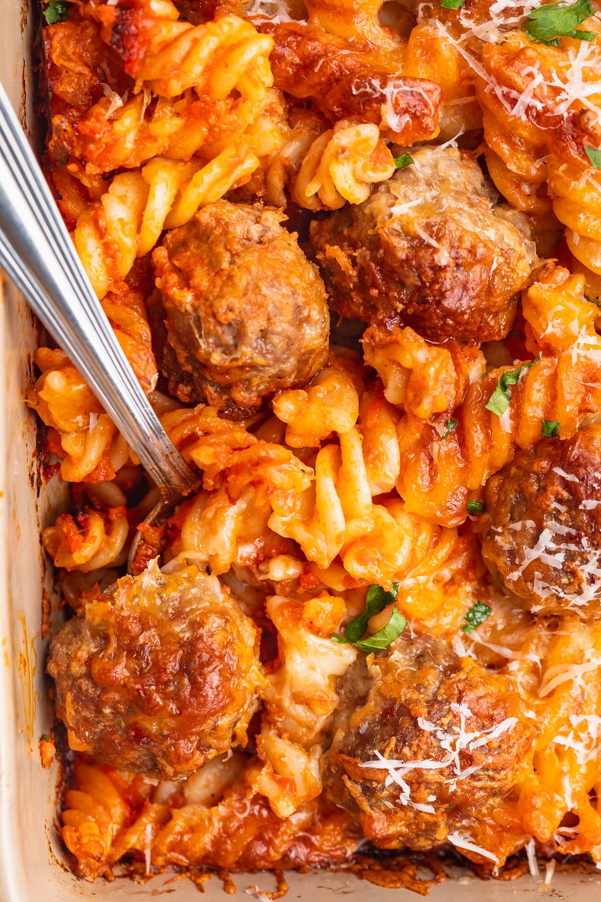 Close-up look at meatball casserole with rotini noodles, red sauce, and cheese.