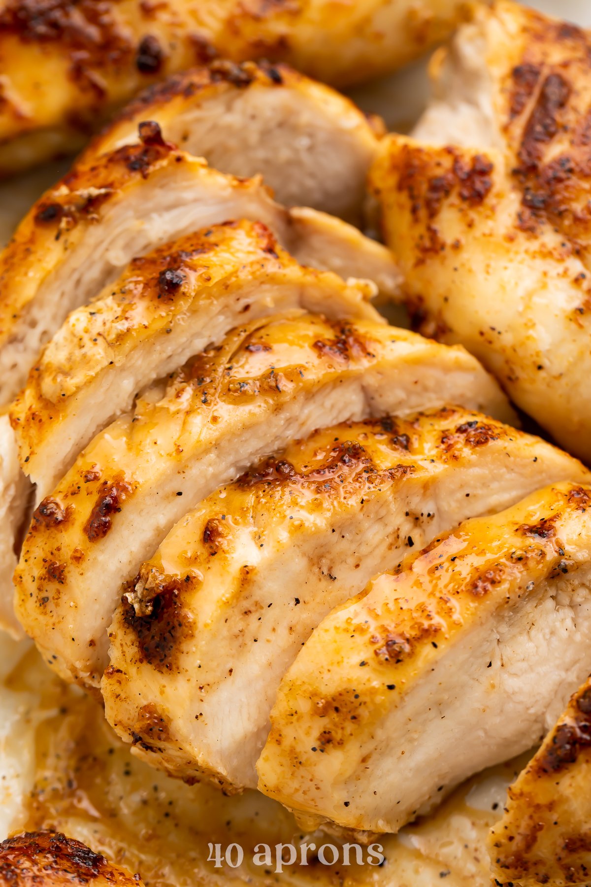 Air fryer frozen chicken breast sliced thin and lined up on a cutting board.