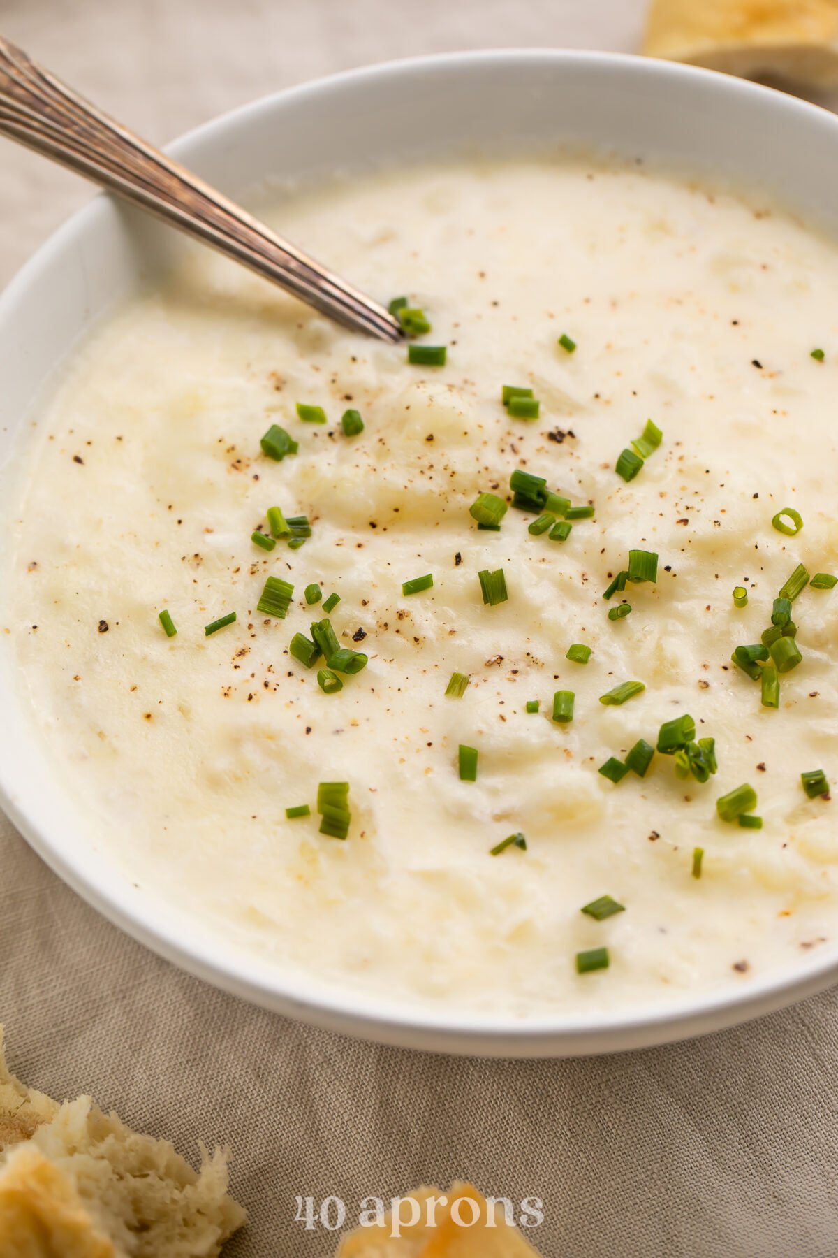 Angled view of a bowl of creamy old-fashioned potato soup topped with green onions.