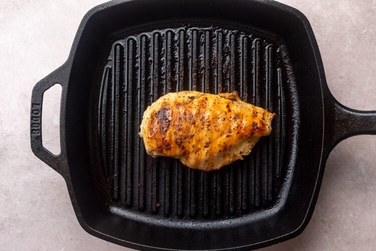 Grilled, seasoned chicken breast on a large grill pan.