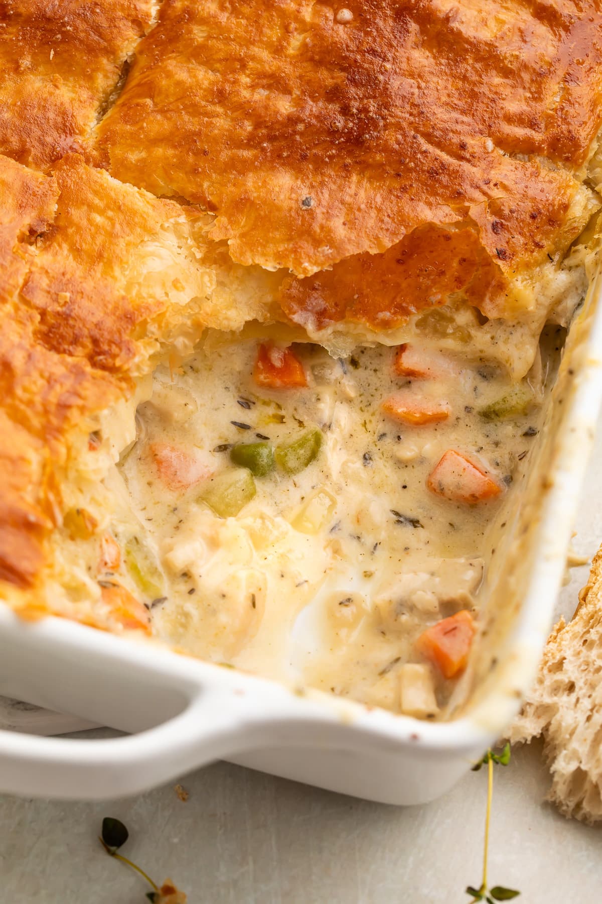Chicken pot pie casserole in a square dish, with a corner scooped out to show some of the filling.