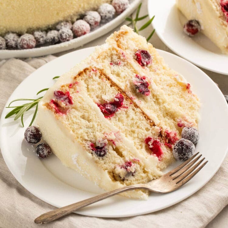 White chocolate cranberry cake slice on a plate.